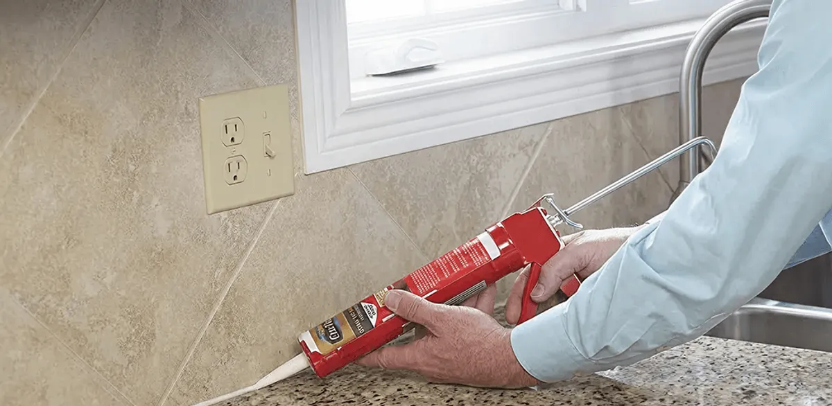 Handyman applying caulk along a kitchen backsplash and countertop seam in Boise, ID