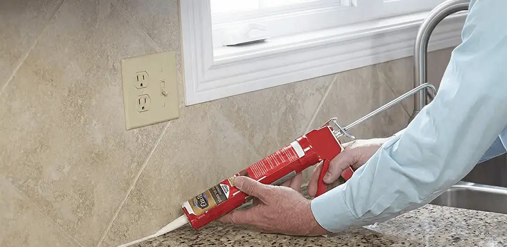 Handyman applying caulk along a kitchen backsplash and countertop seam in Boise, ID
