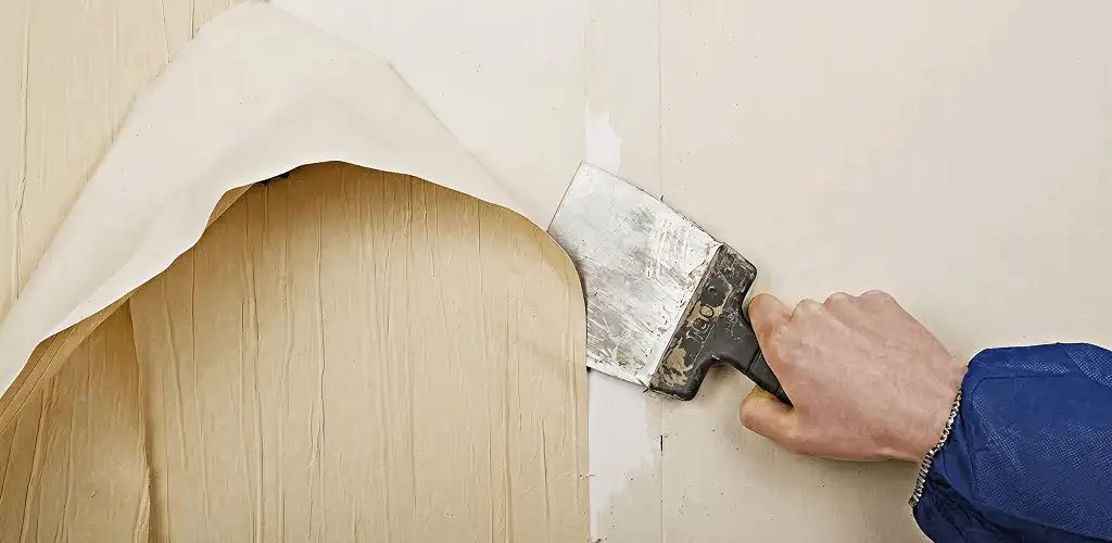 Handyman removing wallpaper with a scraper for wall preparation in Boise, ID