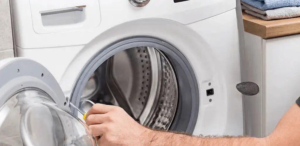 Handyman repairing a front-load washing machine and inspecting the drum in Boise, ID